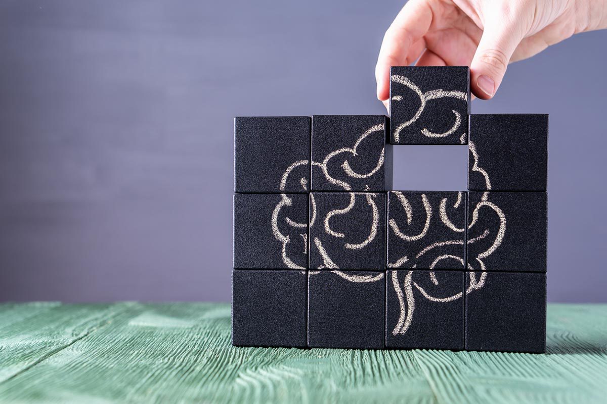 Hand placing last puzzle piece depicting human brain.